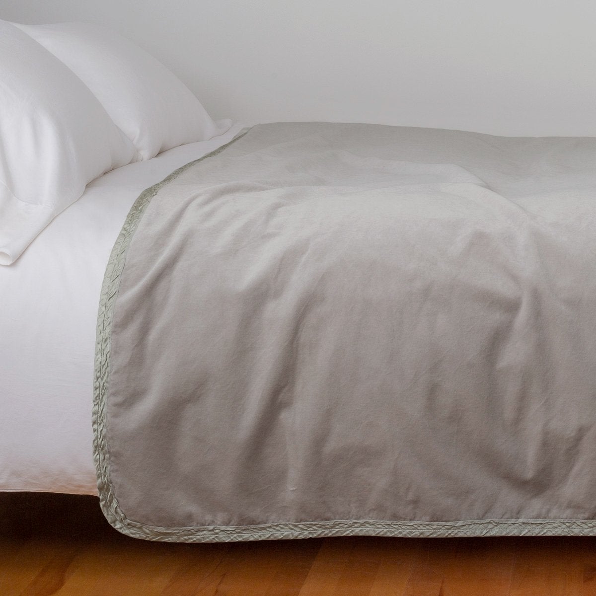 Fog: Cotton velvet bed end sized blanket, draped on a white bed - side view.