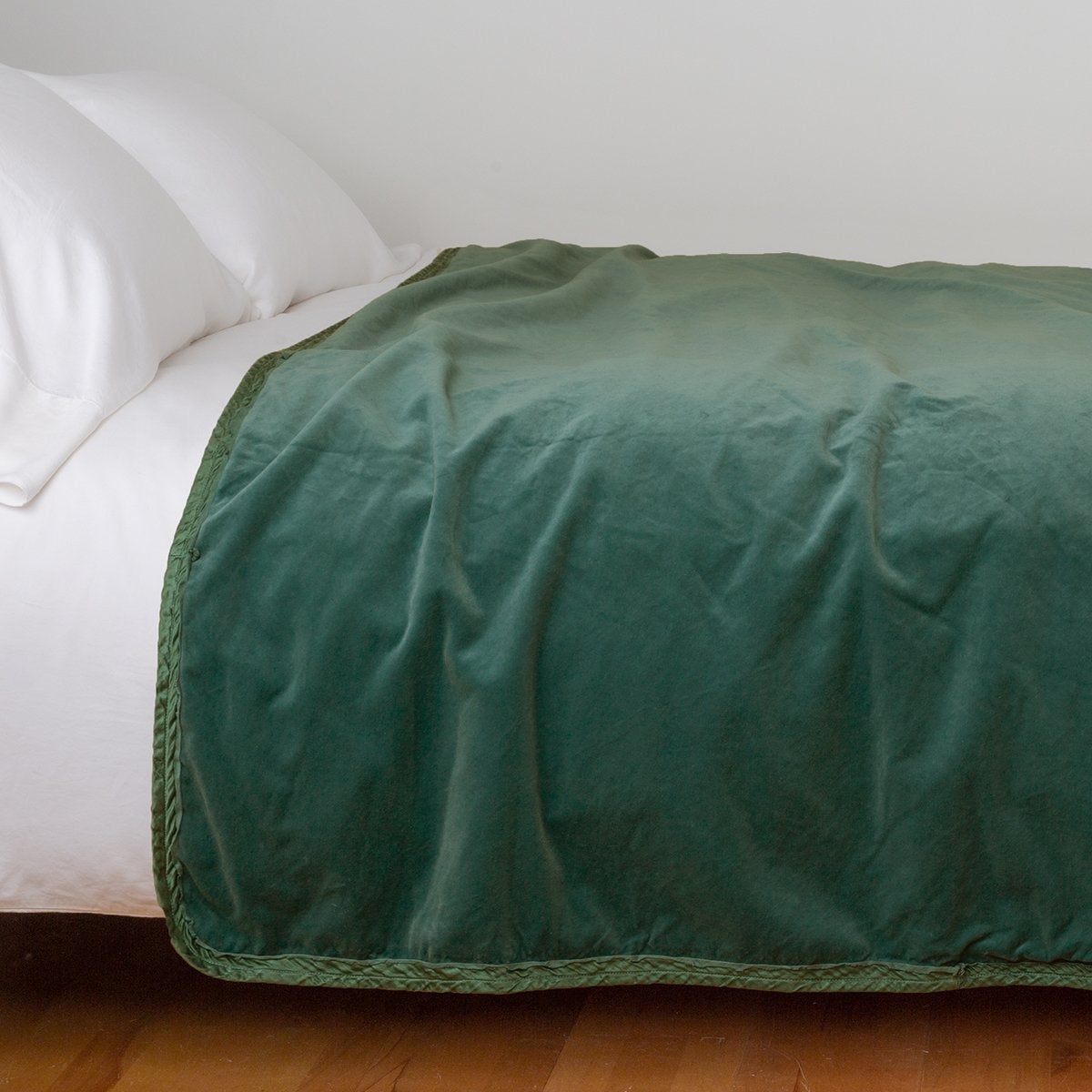 Jade: Cotton velvet bed end sized blanket, draped on a white bed - side view.