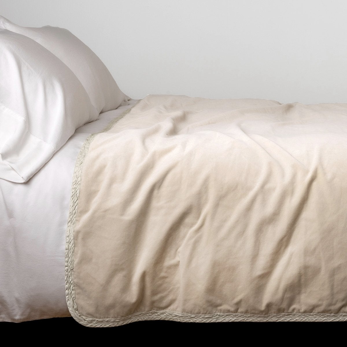 Parchment: Cotton velvet bed end sized blanket, draped on a white bed - side view.