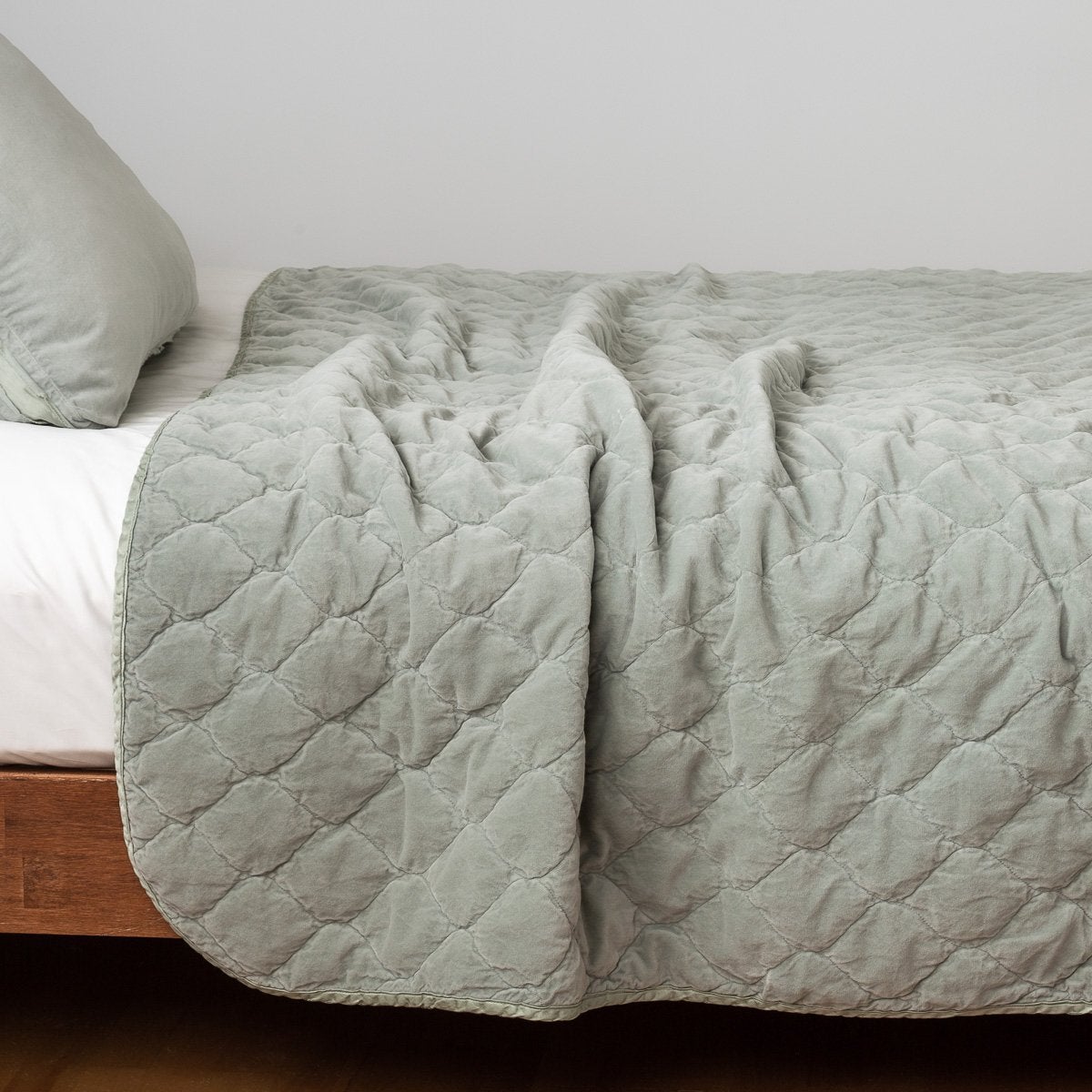 Eucalyptus: Quilted cotton velvet coverlet draped over a white fitted sheet - side view.