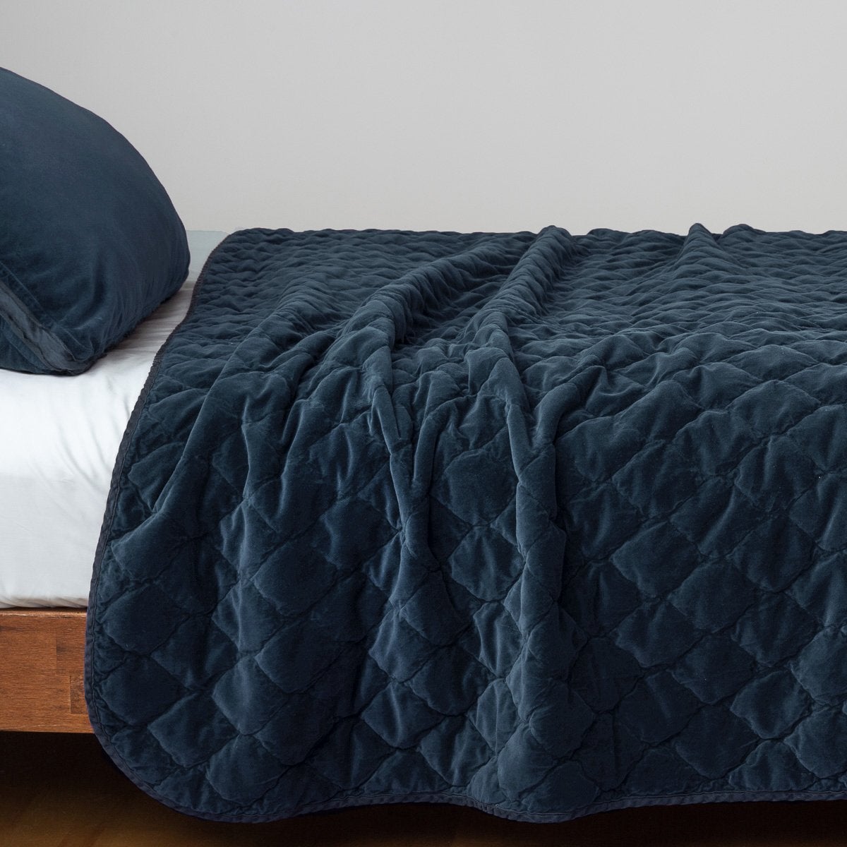 Midnight: Quilted cotton velvet coverlet draped over a white fitted sheet - side view.