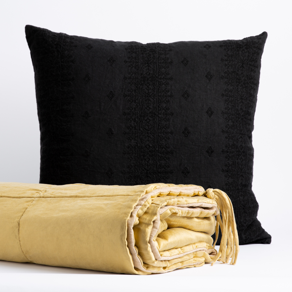 [allvariants]: Taline bed end blanket in honeycomb folded with tassel on corner showing against an ines throw pillow in corvino - front view with white background. 