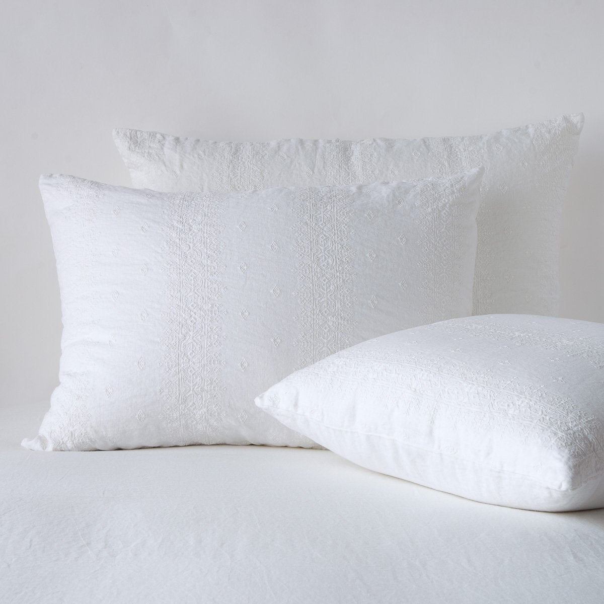 White: two shams leaning upright and one laying flat at an angle, against a white background.