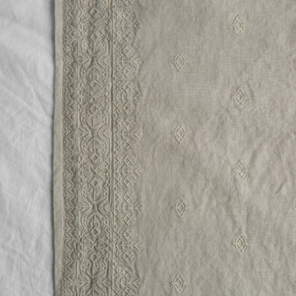 Sterling: A close up of Ines, midweight linen with cotton embroidery, in sterling, a silvery neutral light grey. 