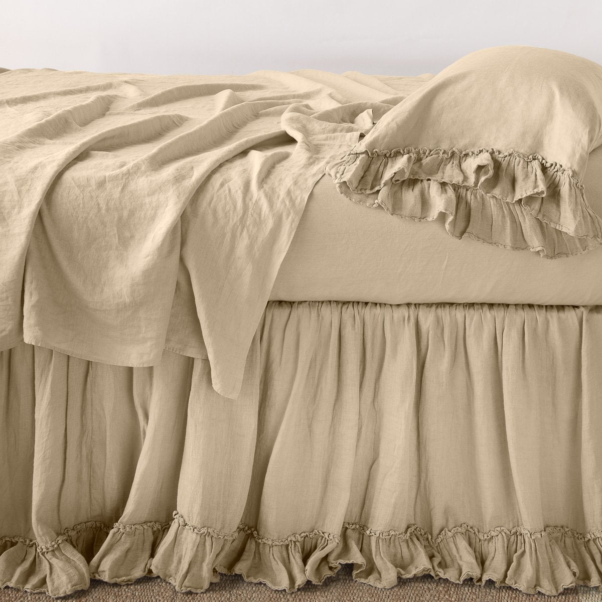 Honeycomb: bed skirt layered with monochromatic linen sheeting - side view.