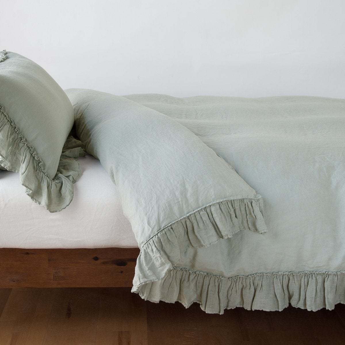 Eucalyptus: duvet cover folded back over a white fitted sheet, shown with matching sham against a plain background - side view.
