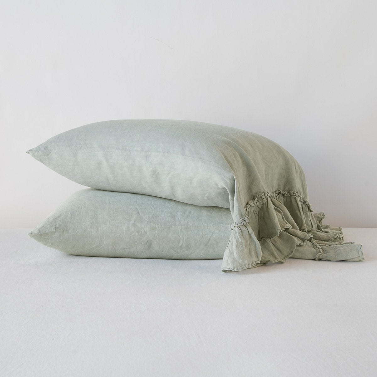 Eucalyptus: Two sleeping pillows stacked at a slight angle against a plain background, showcasing ruffle trim detail - side view.