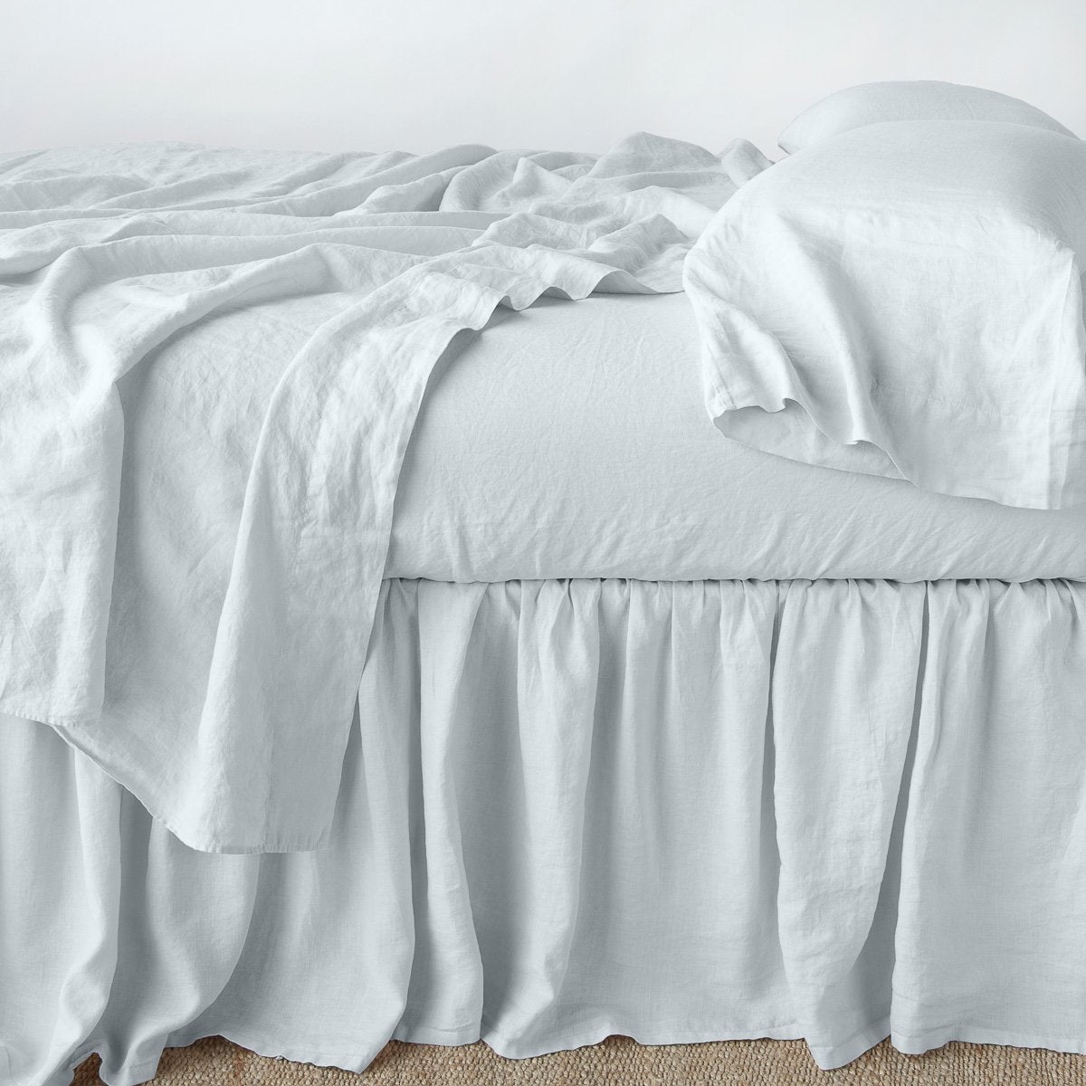 [allvariants]: Linen bed skirt in cloud, with matching rumpled sheets and sleeping pillows - side view.