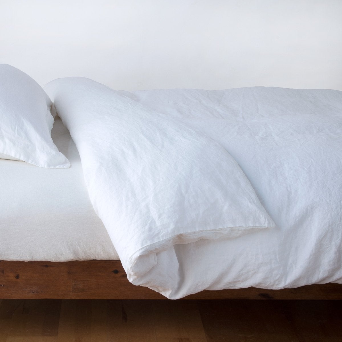 White: duvet cover neatly folded back over white linen sheeting - side view.