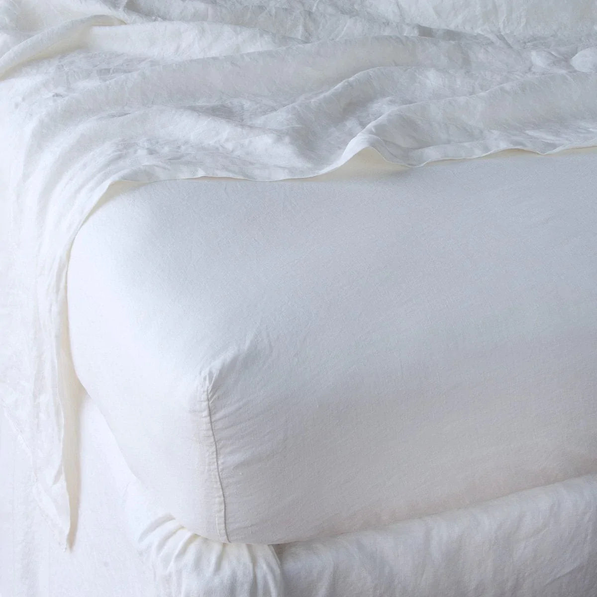 White: close up of fitted sheet with matching rumpled flat sheet - corner view.