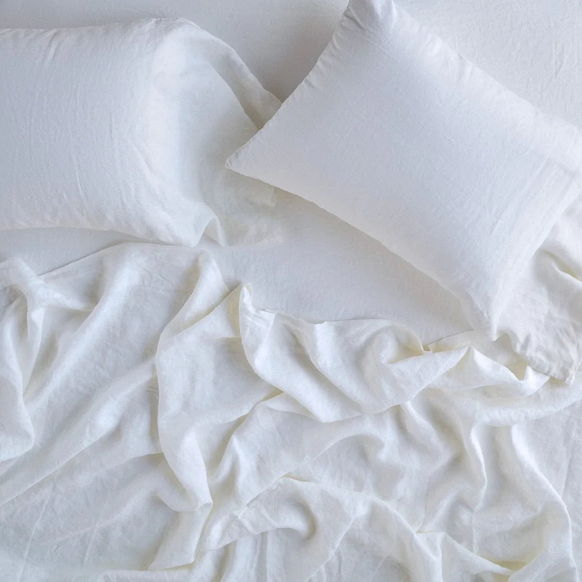 White: Rumpled sheeting with matching sleeping pillows - overhead view.