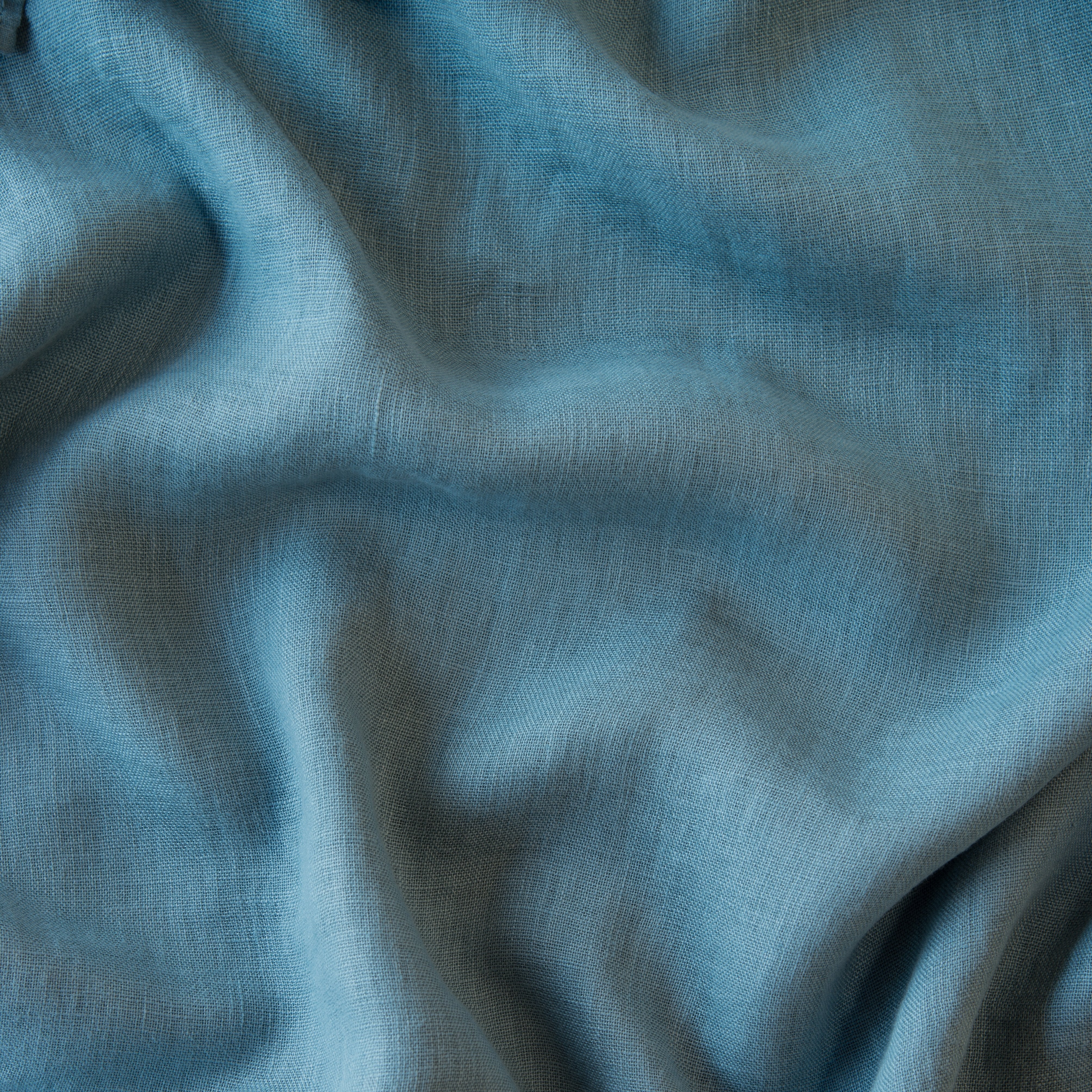 Cenote: A close up of linen whisper, our lightweight linen gauze, in cenote, a vibrant, ocean-inspired blue-green.