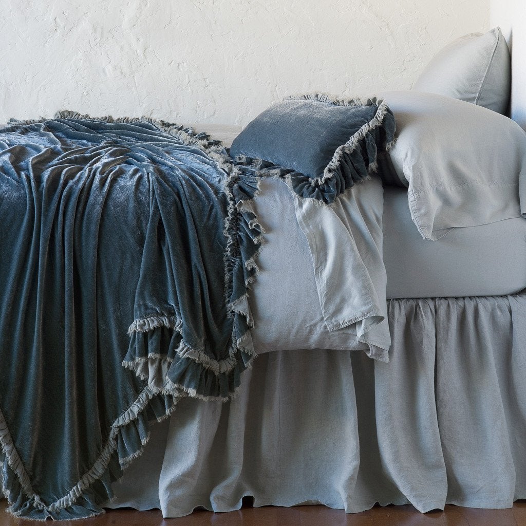 Mineral: throw blanket draped over a monochromatic bed, shown with matching throw pillow - side view.