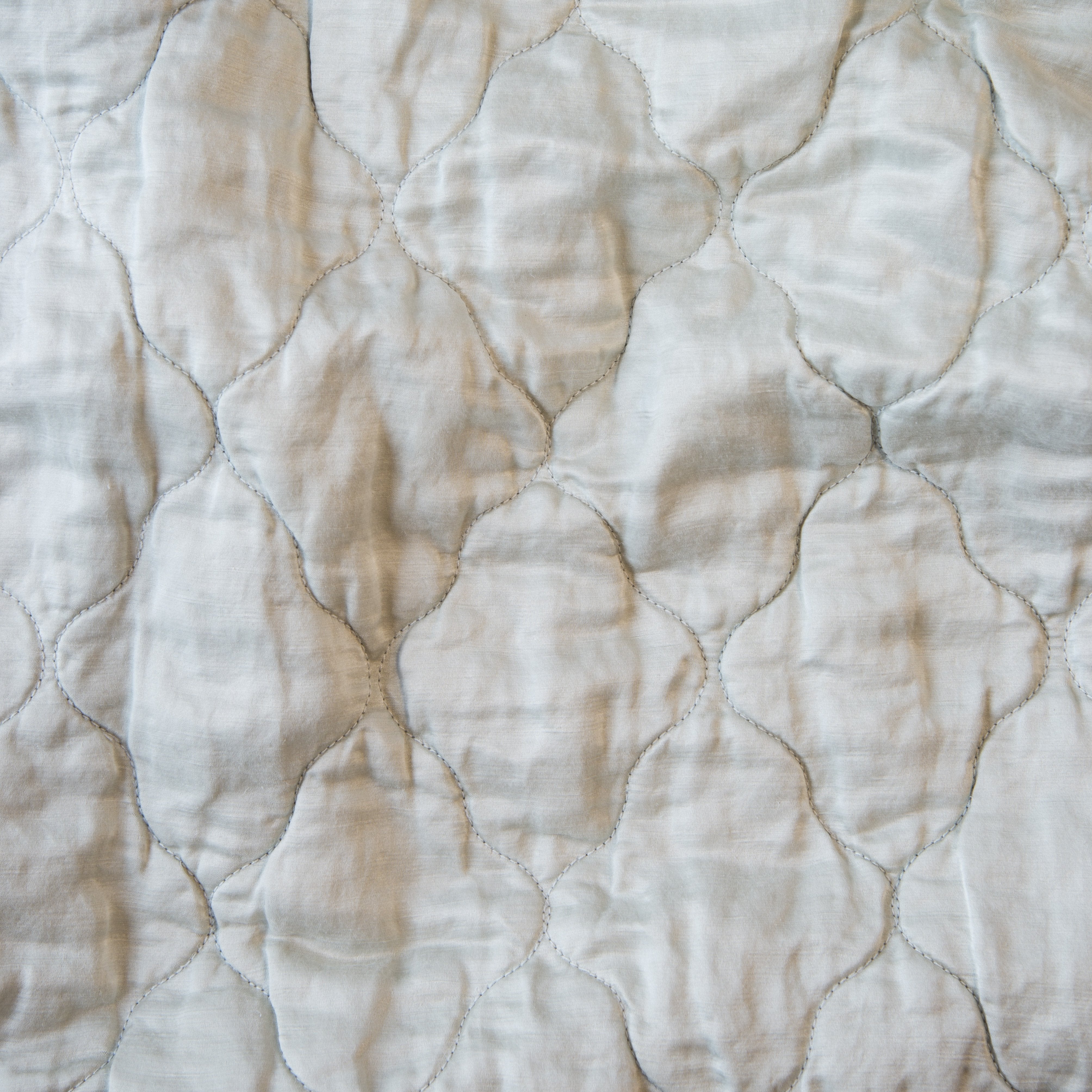 Sterling: Close-up of Luna silk charmeuse quilting in sterling, a silvery neutral light grey. 