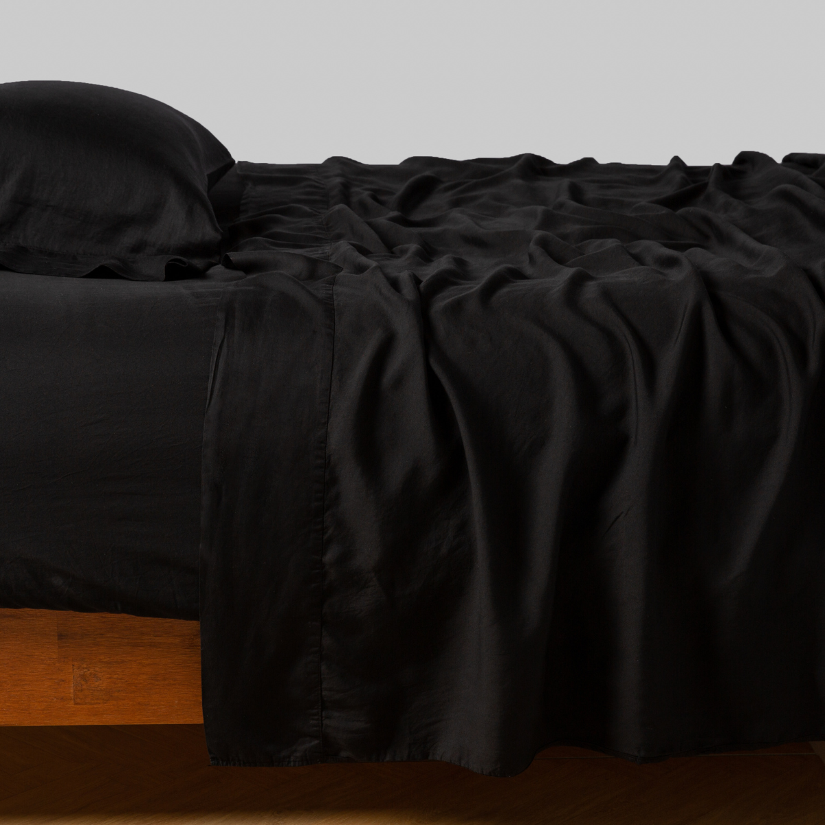 Corvino: Rumpled flat sheet with matching fitted sheet and sleeping pillow - side view.