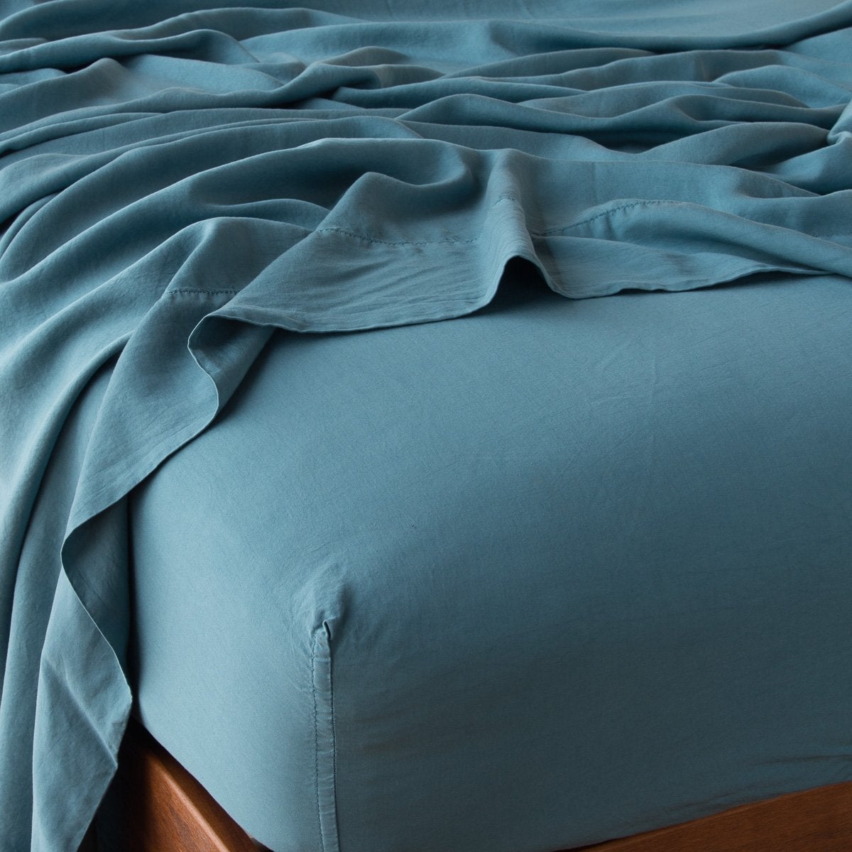 [allvariants]: Madera Luxe fitted sheet in cenote with matching rumpled flat sheet - shown from top corner.
