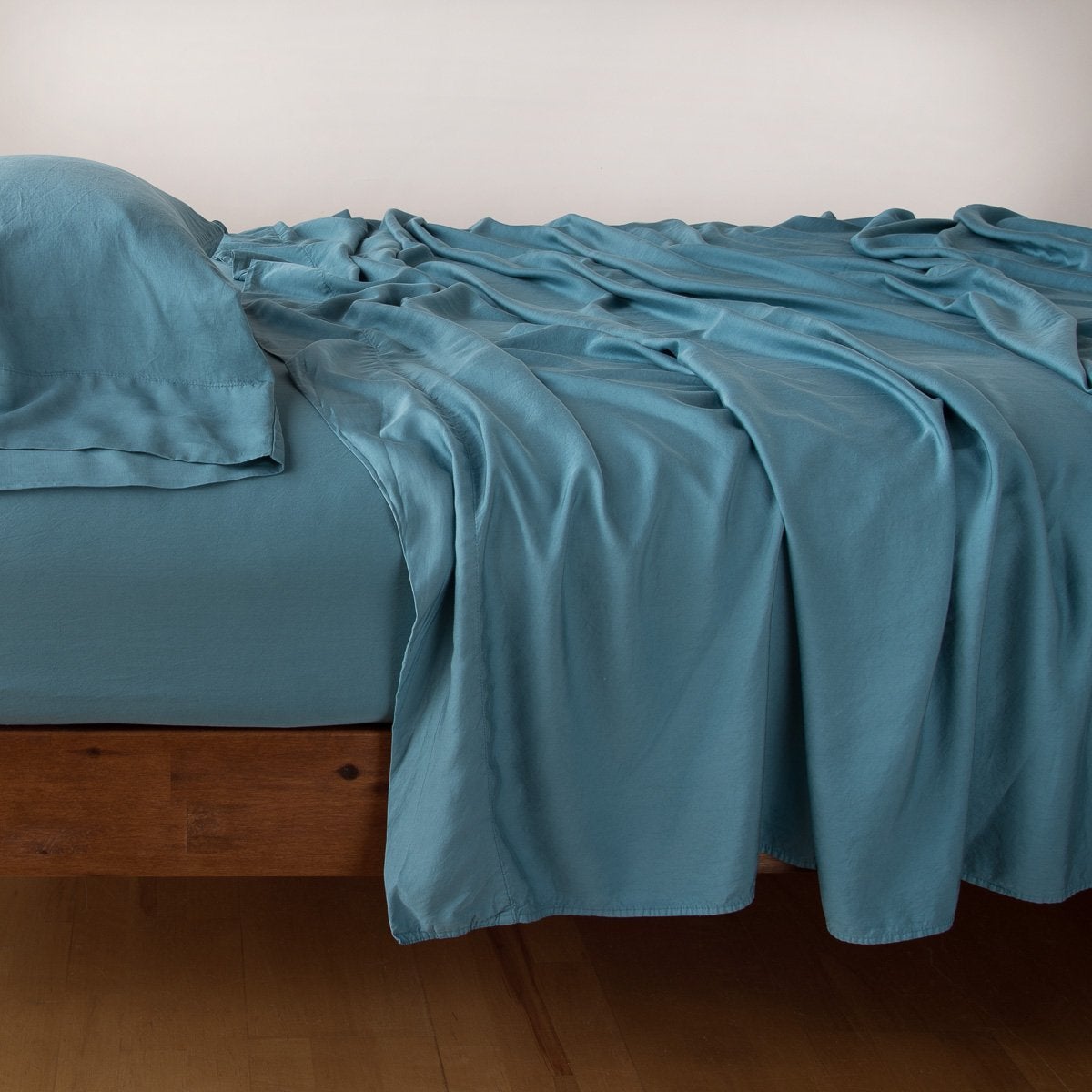 Cenote: Rumpled flat sheet with matching fitted sheet and sleeping pillow - side view.