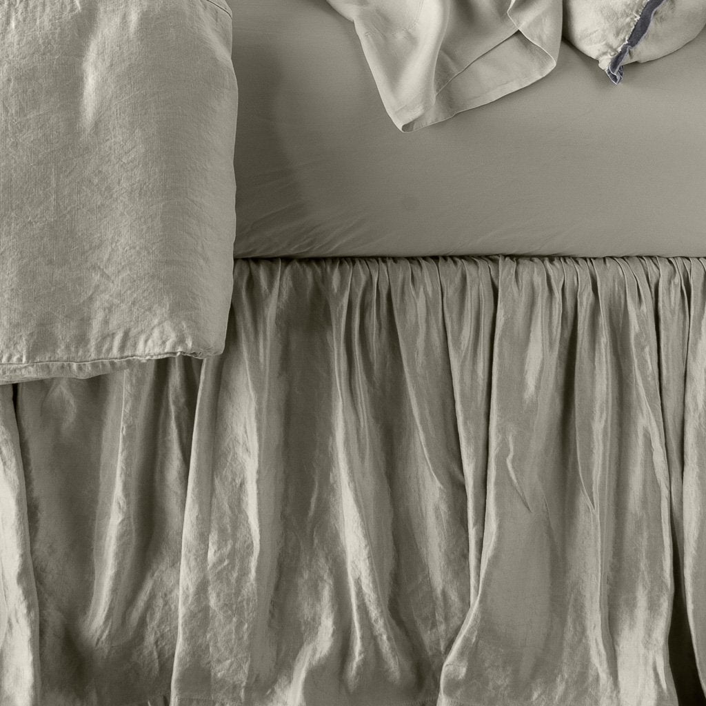 : Close up of Paloma bed skirt, highlighting the shimmering fabric and the gathering detail - fog, side view.