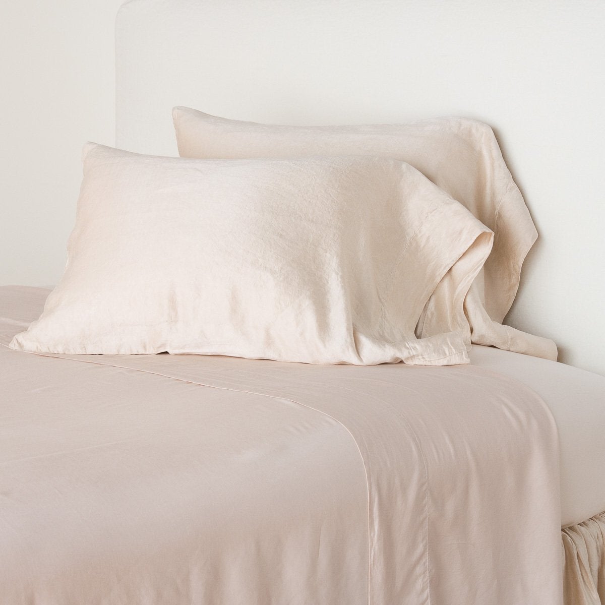 Pearl: sleeping pillows leaning upright against a white wall on monochromatic sheeting - cropped three-quarter angle.
