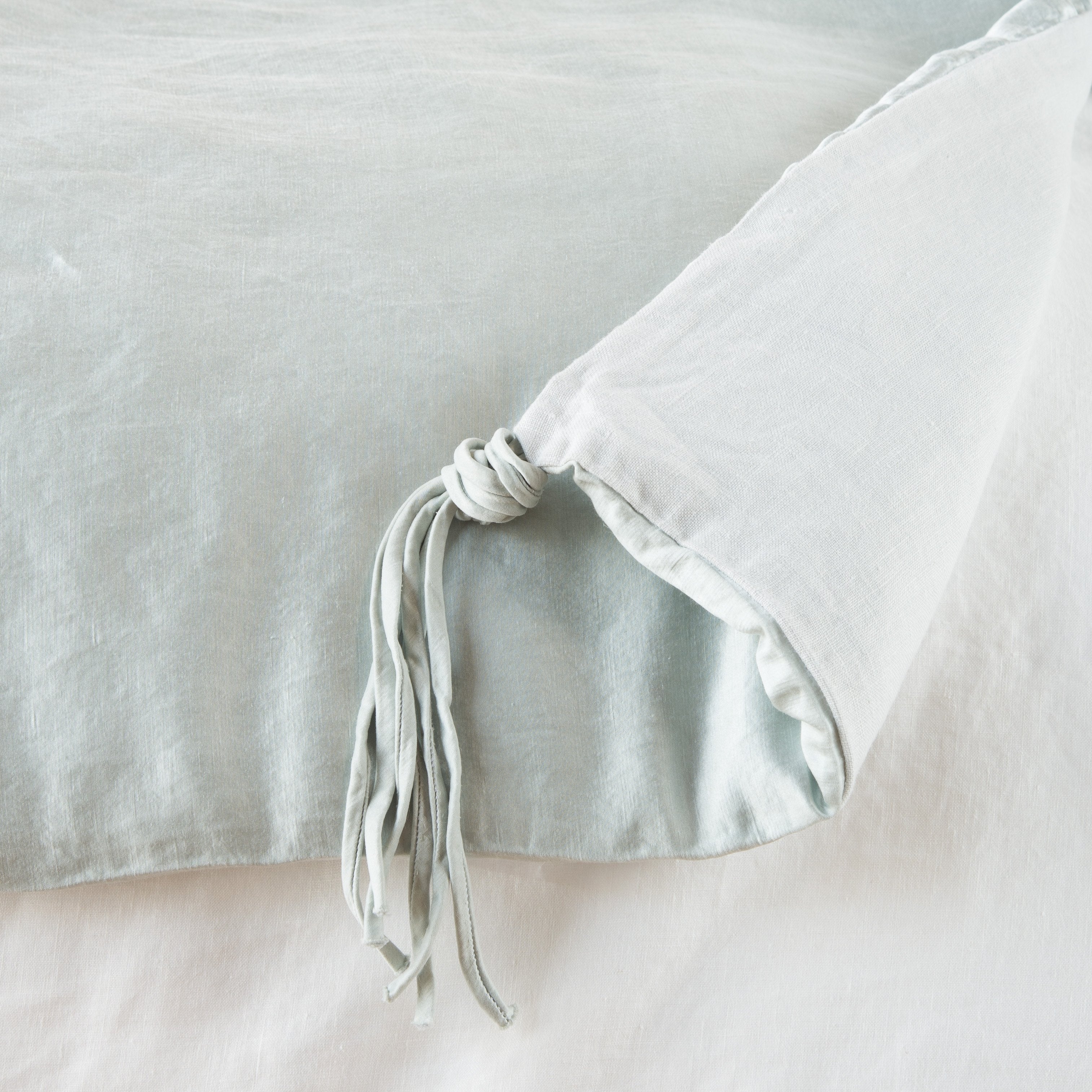 Cloud: Close up of blanket, with a corner turned back to showcase the midweight linen back and corner tassel - overhead view.
