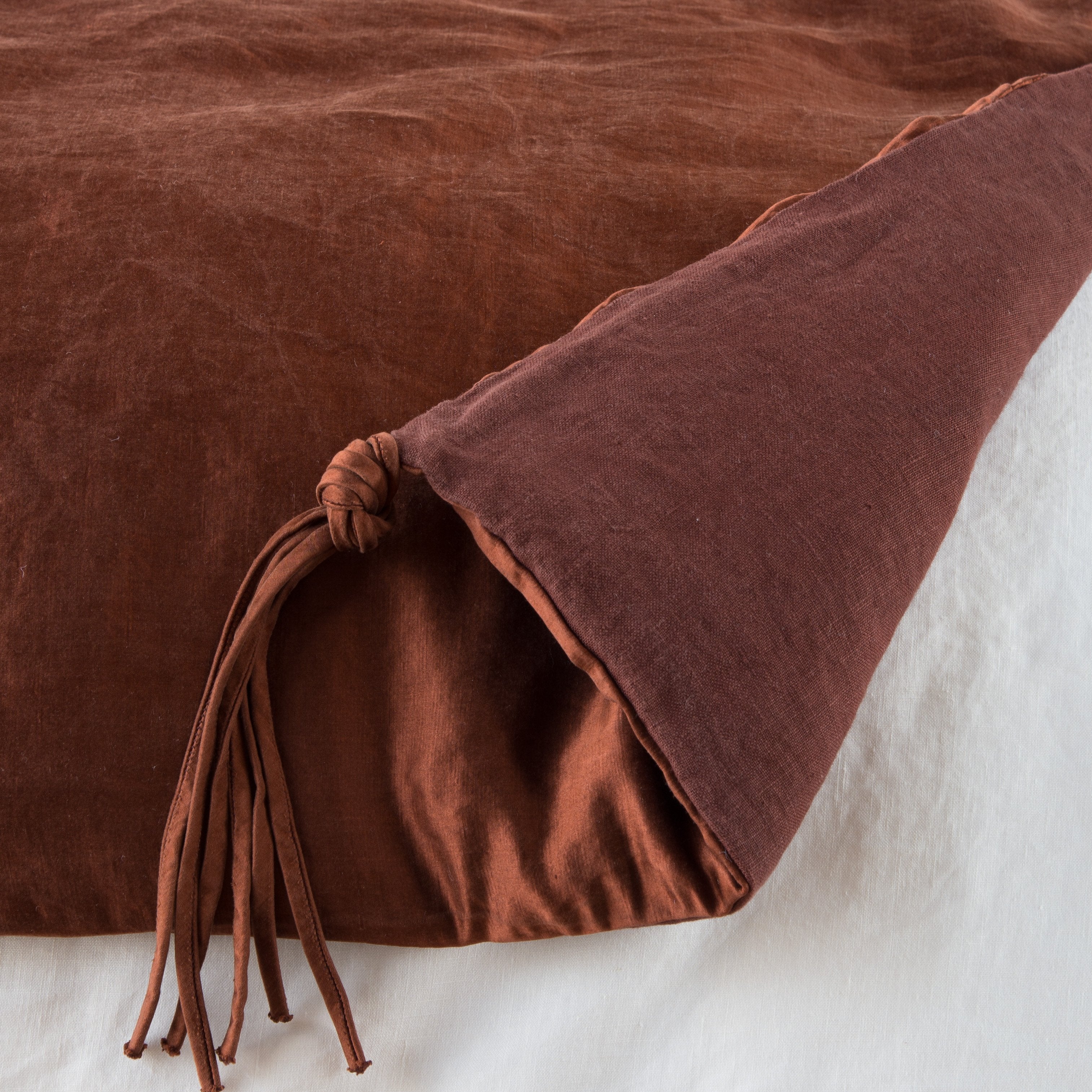Mahogany: Close up of blanket, with a corner turned back to showcase the midweight linen back and corner tassel - overhead view.