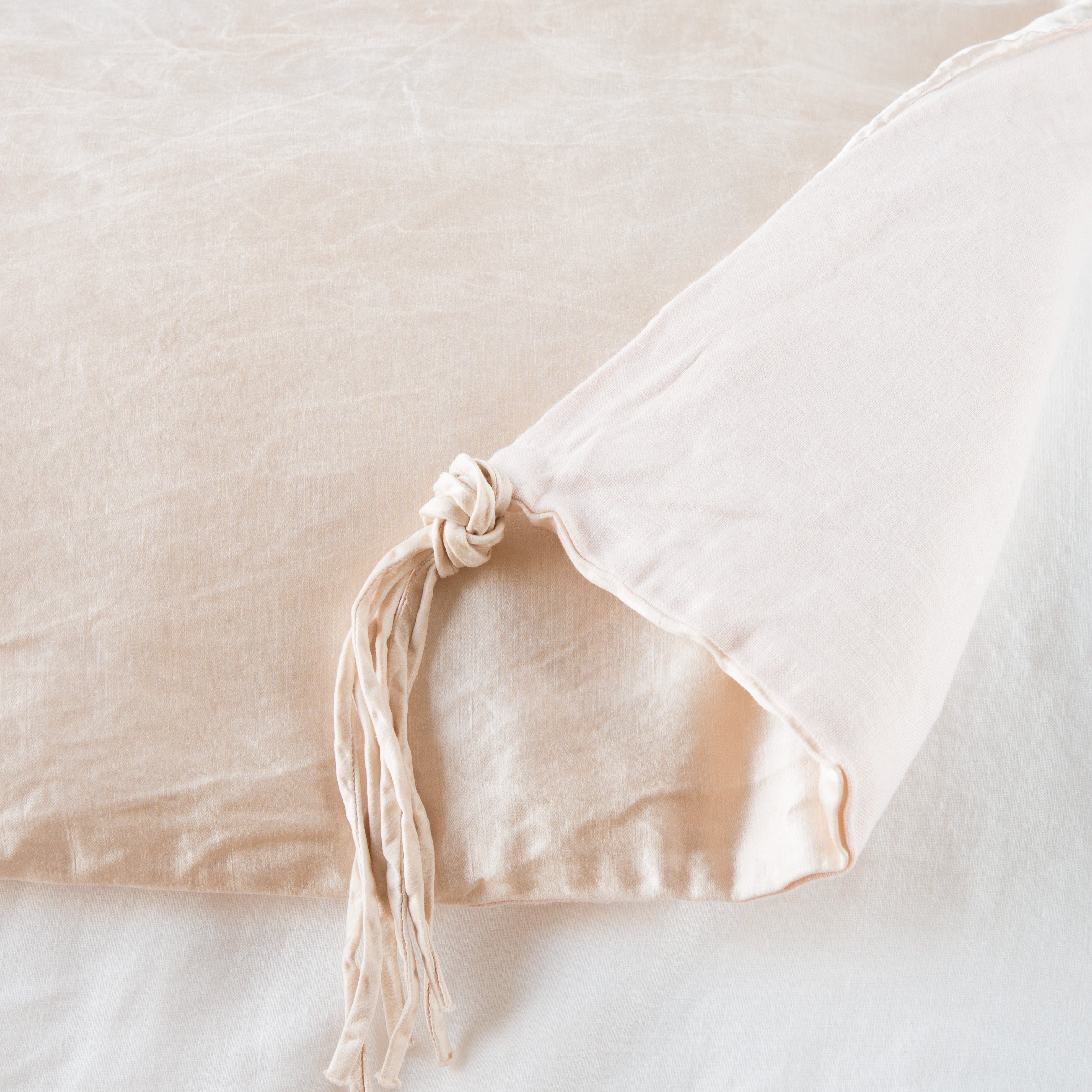 Pearl: Close up of blanket, with a corner turned back to showcase the midweight linen back and corner tassel - overhead view.